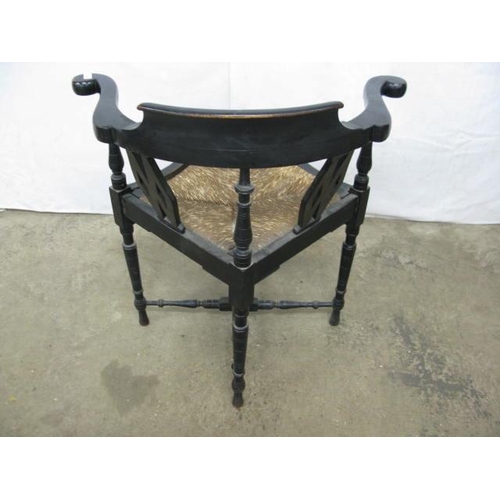 410 - Ebonised corner chair having shaped arms, pierced splats and rush seat, standing on turned legs with... 