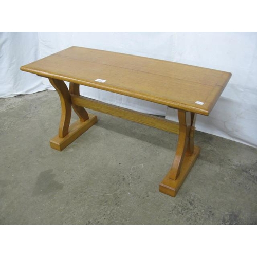 413 - Light oak coffee table standing on shaped trestle legs with a cross stretcher - 81cm x 36.5cm x 43cm... 