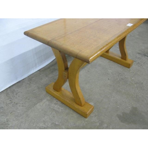 413 - Light oak coffee table standing on shaped trestle legs with a cross stretcher - 81cm x 36.5cm x 43cm... 