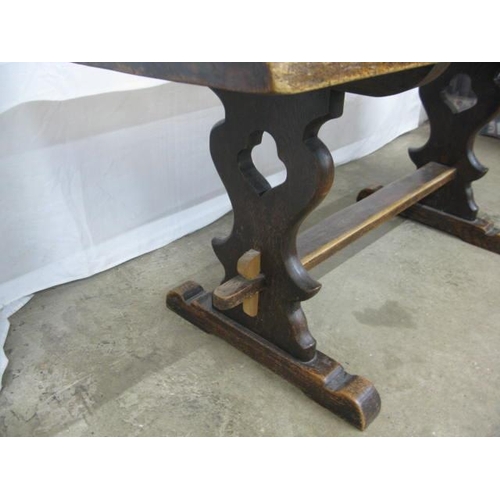 417 - Oak refectory table, the rectangular top standing on shaped pierced trestle legs with a hole and peg... 