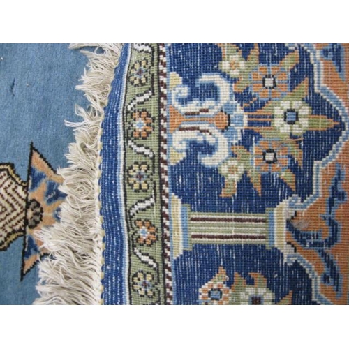 482 - Blue and cream ground patterned prayer rug having a central design with flowers in an urn flanked by... 