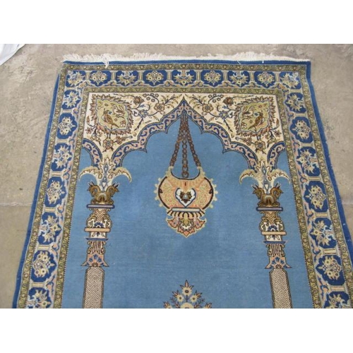 482 - Blue and cream ground patterned prayer rug having a central design with flowers in an urn flanked by... 