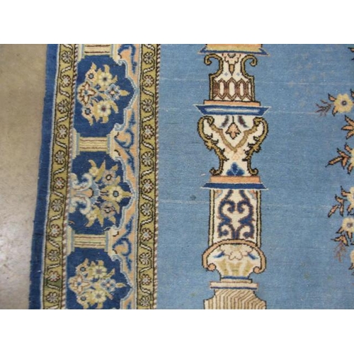 482 - Blue and cream ground patterned prayer rug having a central design with flowers in an urn flanked by... 