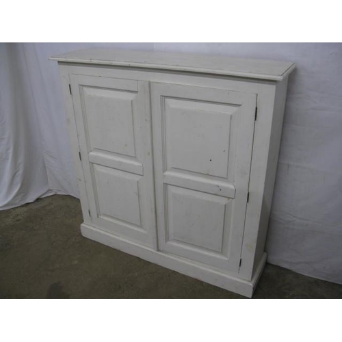 492 - Painted pine cupboard having two panelled doors opening to two fixed shelves, standing on a plinth b... 