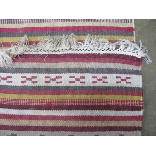 506 - Stripey patterned rug with geometric repeating motifs and end tassels - 2.98m x 2m