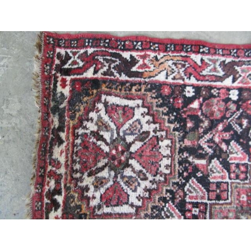 536 - Red ground patterned rug having five central motifs surrounded by geometric shapes and patterned bor... 