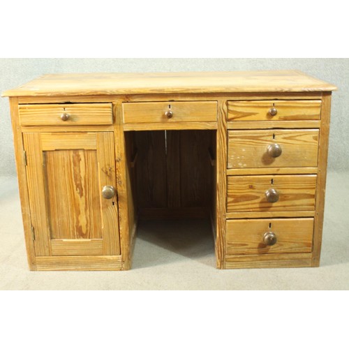 484 - A Victorian pitch pine kneehole desk, with three short drawers, over a cupboard door to one pedestal... 