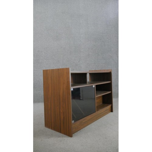 214 - A circa 1970s walnut record cabinet, with an arrangement of shelves and recesses, and a smoked glass... 