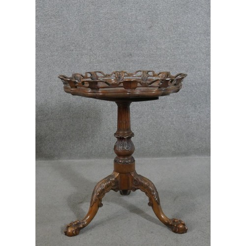 215 - A Victorian walnut tripod table, the hexagonal tilt top with an ornately carved and pierced edge, on... 