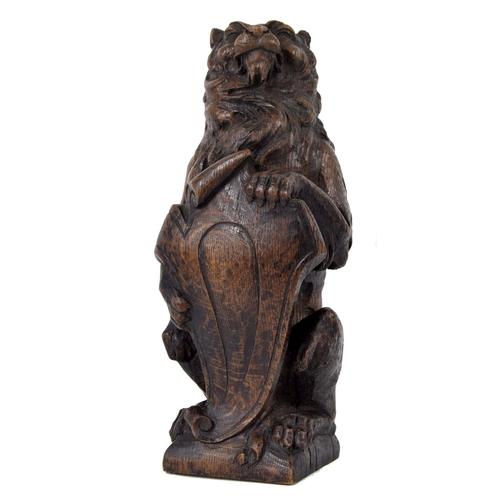 318 - 17th century carved oak lion, modelled holding a scrolling shield, 14