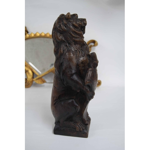 318 - 17th century carved oak lion, modelled holding a scrolling shield, 14