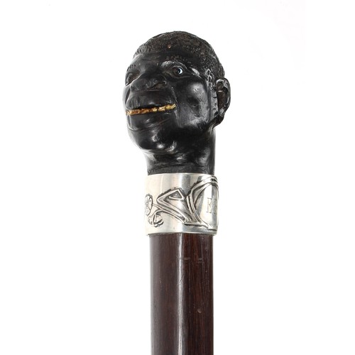 639 - Silver mounted walking cane, the handle/pommel carved as a gentleman, the silver collar marked '800'... 