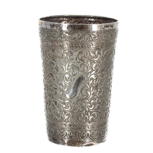 610 - Eastern white metal beaker, the straight sides with close repousse foliate scrolling decoration to t... 