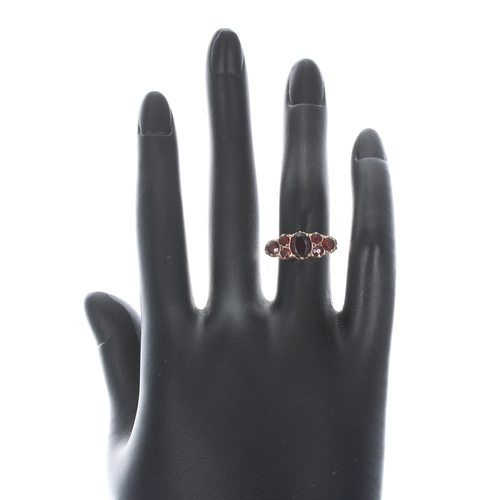 123 - Yellow gold scroll set garnet ring, width 8mm, 2.8gm, ring size L/M