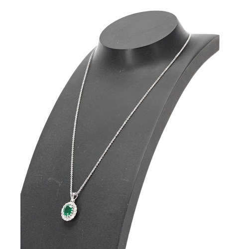 260 - Modern 18ct white gold oval emerald and diamond cluster pendant on a silver chain, the oval emerald ... 