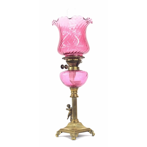 569 - Victorian brass and cranberry glass oil lamp, with fluted flared shade and glass font raised on a pi... 