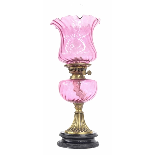 570 - Victorian brass and cranberry glass font oil lamp with fluted flared shade, raised on pottery circul... 