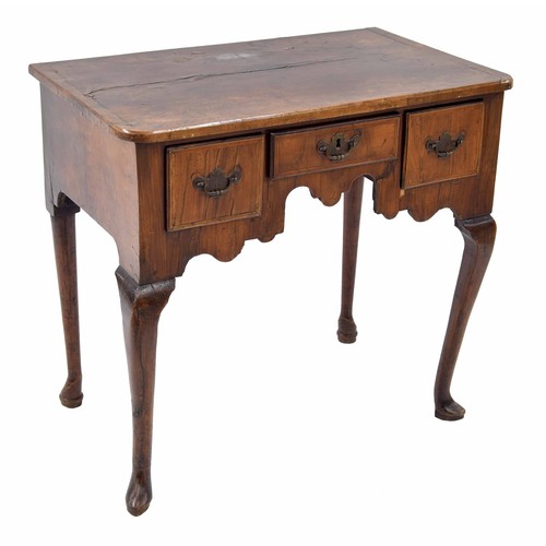 873 - Georgian walnut low boy, the quarter veneered top over three short drawers and shaped frieze raised ... 