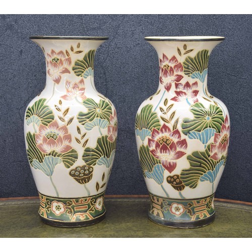 720 - Pair of large decorative pottery vases, with relief decorated lily flower decoration on a pale groun... 