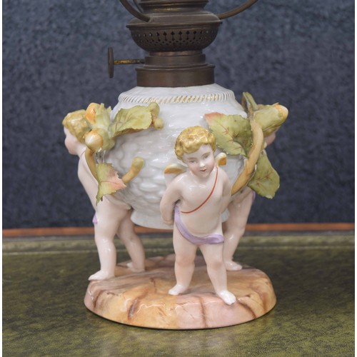 722 - Similar pair of Sitzendorf figural porcelain oil table lamps, modelled with cherubs supporting the w... 