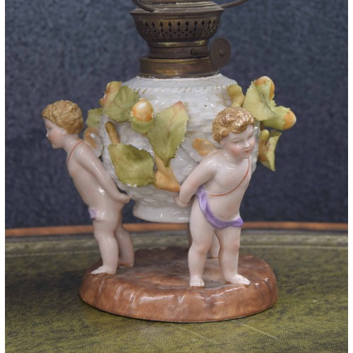 722 - Similar pair of Sitzendorf figural porcelain oil table lamps, modelled with cherubs supporting the w... 