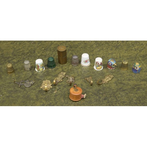 695 - Treen miniature tape measure in the form of a fishing reel; together with a selection of thimbles, m... 