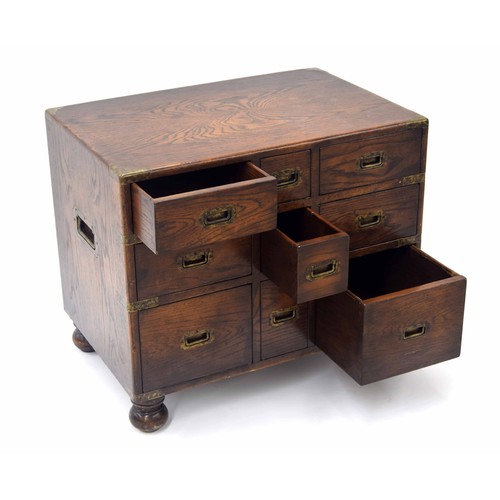 850 - Oak campaign style chest of drawers of small proportions, with brass bound corners and recessed carr... 