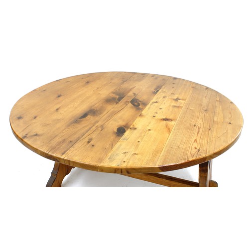 545 - Tony Zemaitis - a circular pitch pine dining table, the shaped underside supports with double heart ... 