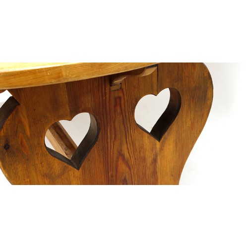 545 - Tony Zemaitis - a circular pitch pine dining table, the shaped underside supports with double heart ... 