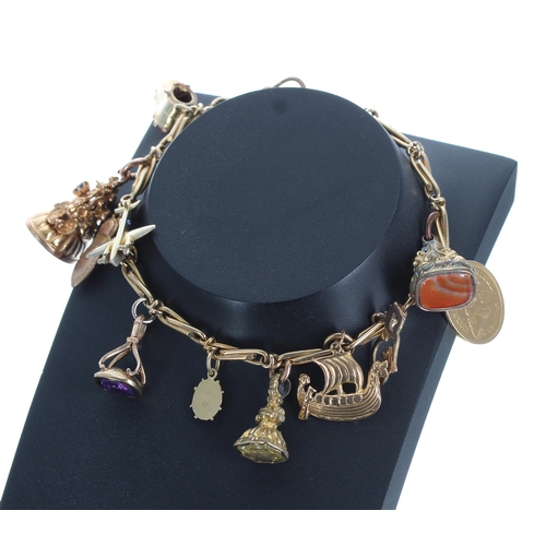 259 - Yellow metal cable link bracelet with an assortment of 9ct and 14ct gold and gilded charms and fobs,... 