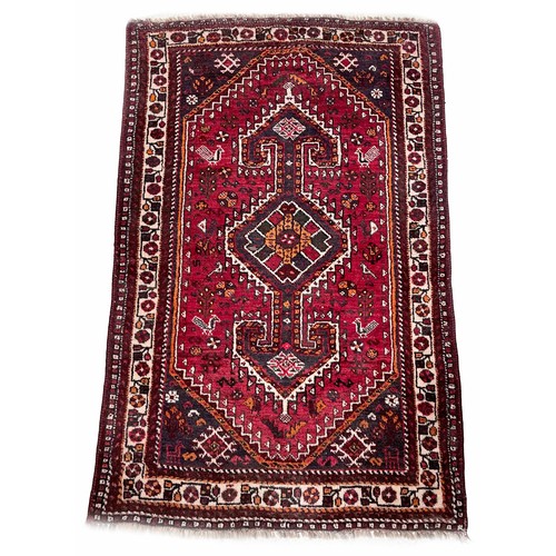 753 - Iranian handmade Shiraz rug, labelled, on a dark red ground, 70