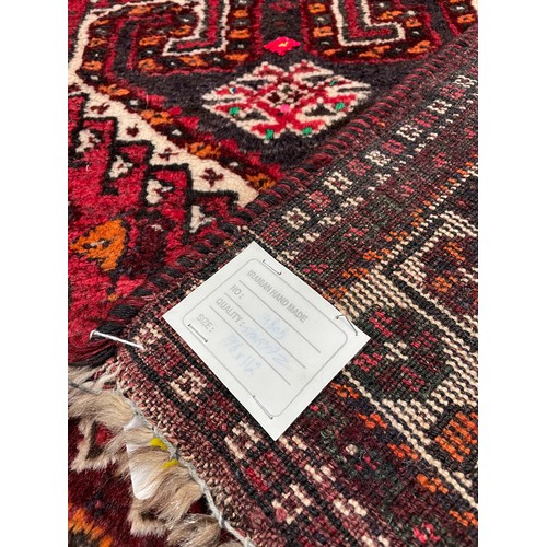 753 - Iranian handmade Shiraz rug, labelled, on a dark red ground, 70