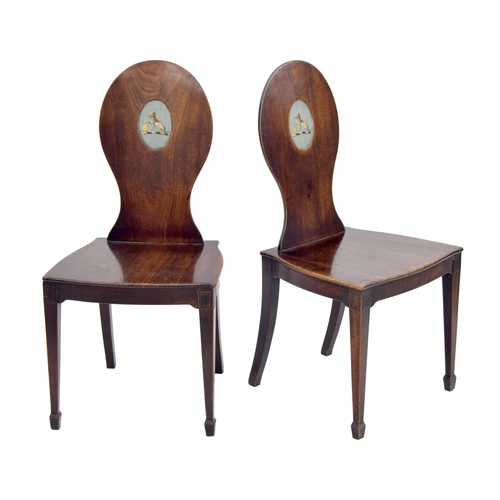 564 - Pair of 19th century mahogany hall chairs, the oval backs each with a recess panel painted with a co... 