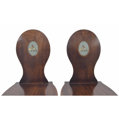 564 - Pair of 19th century mahogany hall chairs, the oval backs each with a recess panel painted with a co... 