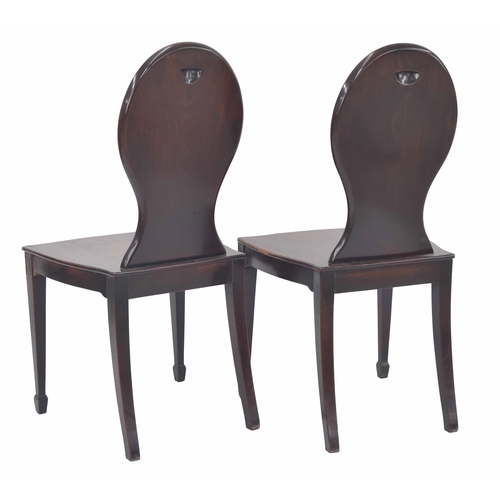 564 - Pair of 19th century mahogany hall chairs, the oval backs each with a recess panel painted with a co... 