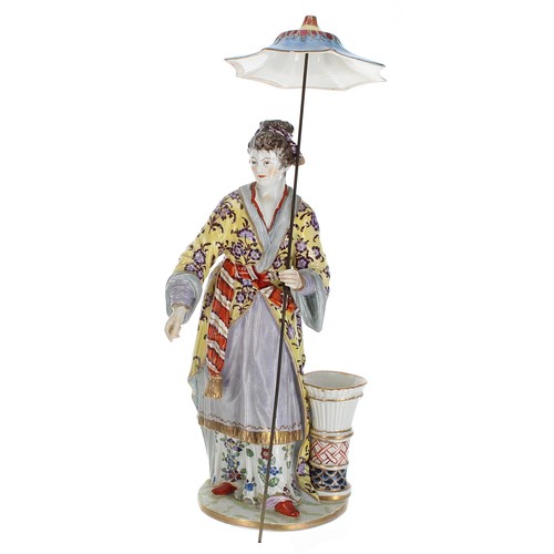 186 - Berlin porcelain figure of a Japanese lady standing holding a parasol, with a pottery vase by her fe... 