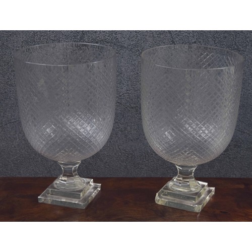 802 - Pair of cut glass urns, in the manner of Waterford, raised on faceted stems over stepped square base... 