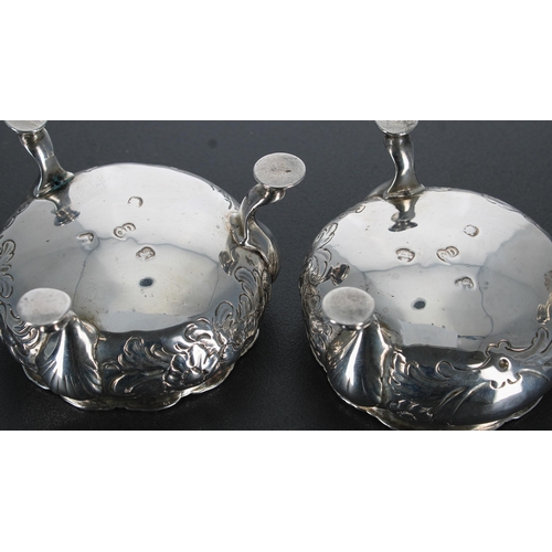 725 - Pair of George III silver salt cellars, with blue glass liners, repousse decorated with flowers and ... 