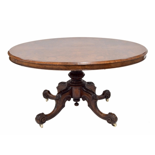 1011 - Victorian walnut oval breakfast table, the quarter veneer mounded tilt top, raised on a carved centr... 