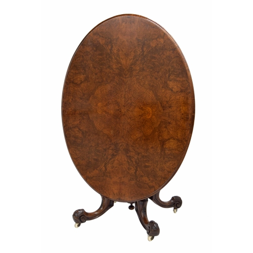 1011 - Victorian walnut oval breakfast table, the quarter veneer mounded tilt top, raised on a carved centr... 