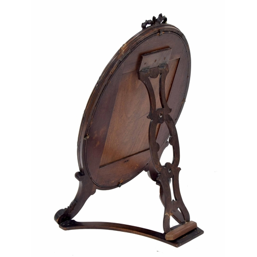 1012 - Mahogany oval strut dressing mirror, the plain glass within a reeded frame surmounted by a carved bo... 