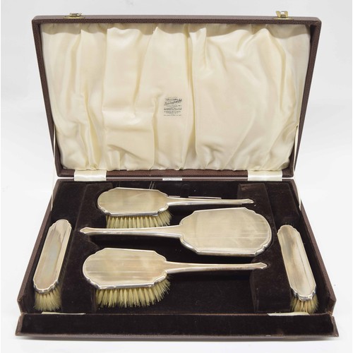 890 - Boxed silver engine turned dressing table set, comprising a hand mirror, four brushes and comb holde... 