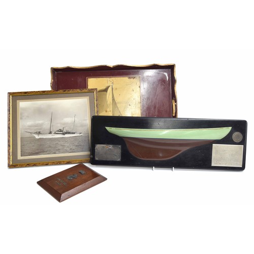559 - Painted wooden half hull model of a yacht, mounted bearing multiple plaque accolades for 'Winner of ... 