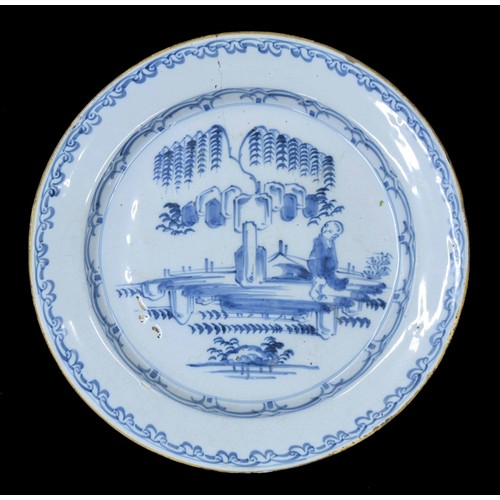 582 - Delft blue and white pottery plate, decorated with a figure in a garden under a tree, within scroll ... 