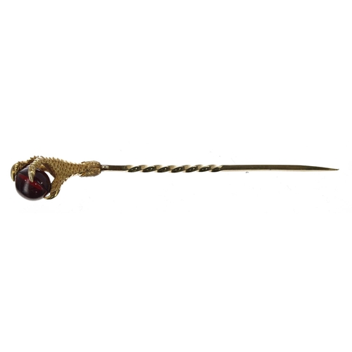 331 - Eagle talon claw stick pin modelled with a garnet sphere, 6.9gm, 82mm long