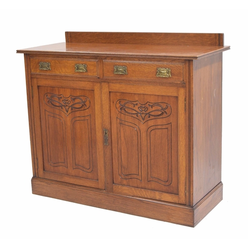 965 - Art Nouveau oak cupboard, the raised back over two drawers with stylised brass handles, over panelle... 