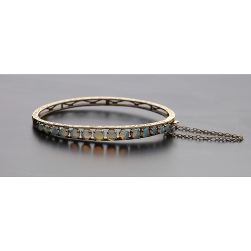 330 - Attractive 9ct engraved bangle set with a channel of graduated cabouchon opals, with safety chain, 1... 