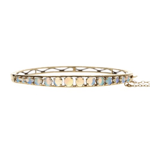 330 - Attractive 9ct engraved bangle set with a channel of graduated cabouchon opals, with safety chain, 1... 