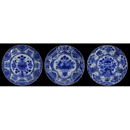 718 - Three Dutch Royal Delft, Porcelyne Fles blue and white pottery chargers, decorated with a flowers, w... 