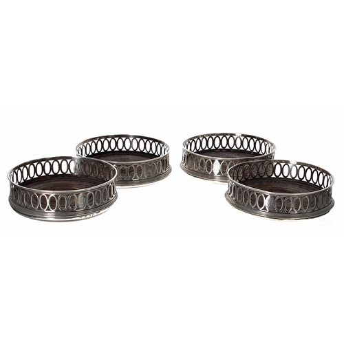 32 - Set of three Georgian silver bottle coasters, the pierced oval rims over a turned hardwood bases wit... 